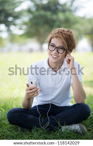 Vertical shot of a guy on leisure relaxing outdoors listening to music