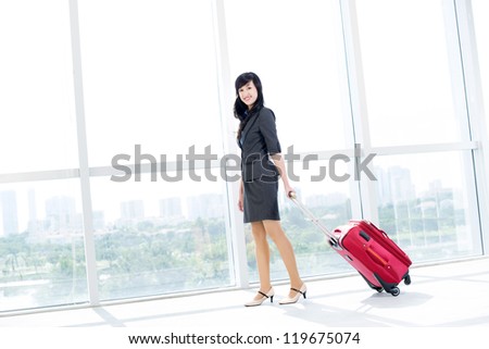 Portrait of young businesswoman with baggage looking at camera in airport