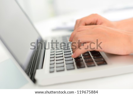 Close-up of female hands typing on the laptop keyboard