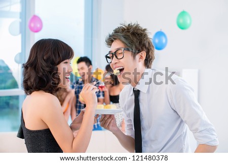 Flirty girl giving piece of cake to a boy