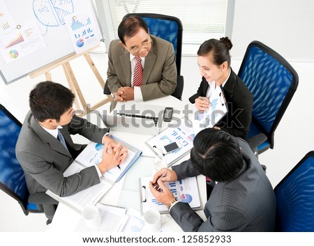 Business team sitting at table and looking at colleague