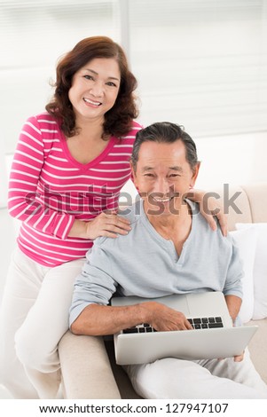 Vertical portrait of modern retirees having no trouble using a laptop