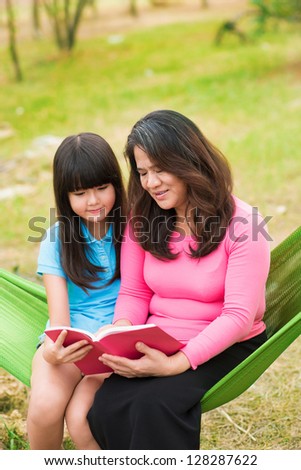 Portrait of a happy mother and a daughter seated in the hammock