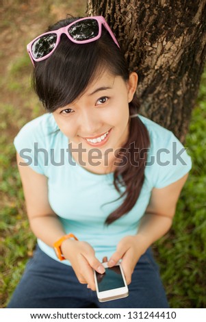 Angle view of a girl with cell phone looking at camera