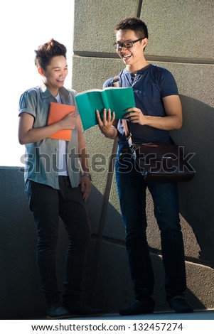 Two students having fun after reading a book outdoors