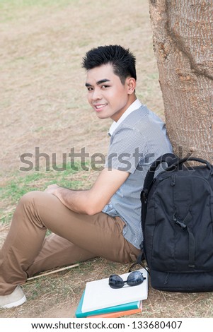 Vertical portrait of a student sitting near the tree outside