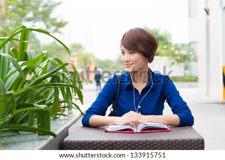 Portrait of a woman at a cafe with a book and headphones