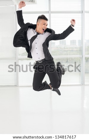 Vertical image of a jumping young asian businessman