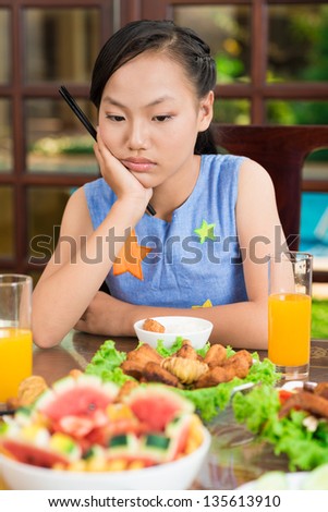Vertical image of a young girl being bored at the family dinner