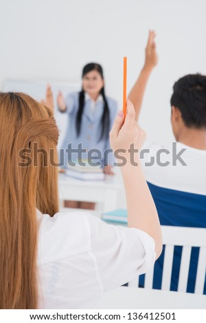 Vertical image of college students raising their hands to answer