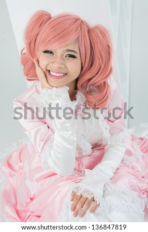 Vertical portrait of a smiling girl wearing silky dress and pink wig in the style of Japanese anime characters