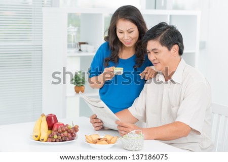 Charming mid-age couple spending morning together reading good news