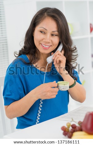 Vertical image of a lovely mid-age woman enjoying her teatime phone conversation