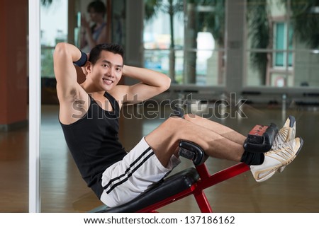 Portrait of an energetic young man doing sit-ups to form nice abs