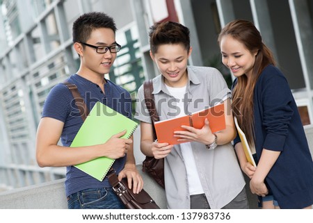 Image of a group of modern students reading a book outside