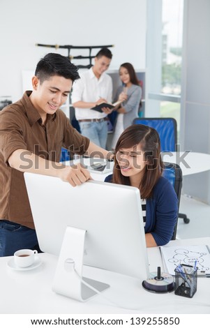 Vertical image of two colleagues in front of the computer on the foreground