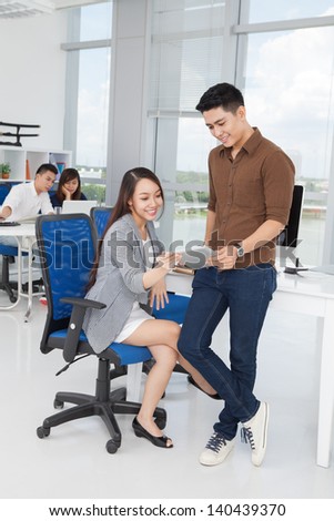 Full-length image of co-workers using a laptop for their work