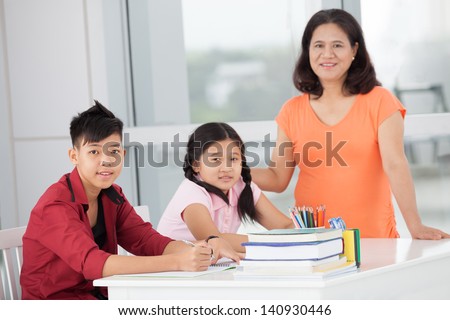 Children and their mum smiling and looking at camera inside