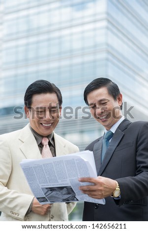 Copy-spaced image of co-workers reading a newspaper and discussing the latest news