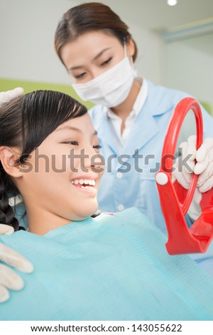 Vertical image of a teenager looking at the teeth in a mirror inside