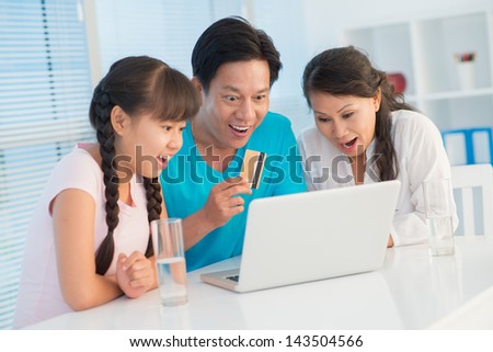 Close-up image of a family full of excitement sitting in front of the laptop with a card at home