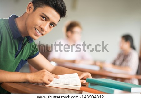 Copy-spaced portrait of a student sitting with books and looking at camera