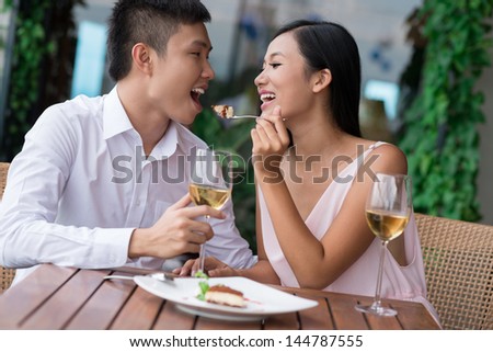Charming lovers sharing a sweet dessert in a cafe