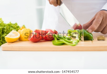 Close-up of human hands cutting pepper on the cutting-board