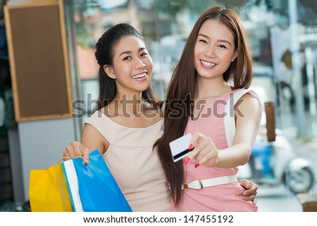 Portrait of lovely girlfriends giving a credit card while paying for her purchase