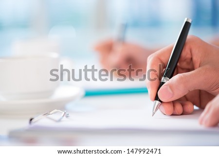 Close-Shot Of A Human Hand Signing A Business Contract On The Foreground