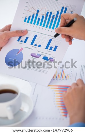 Vertical image of business colleagues discussing business strategy while using diagrams viewed below
