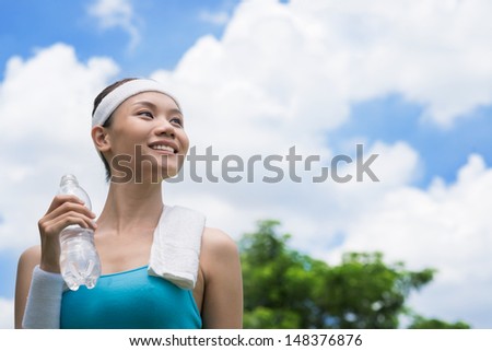 Copy-spaced image of a happy sporty person with a waterbottle in hands over sky