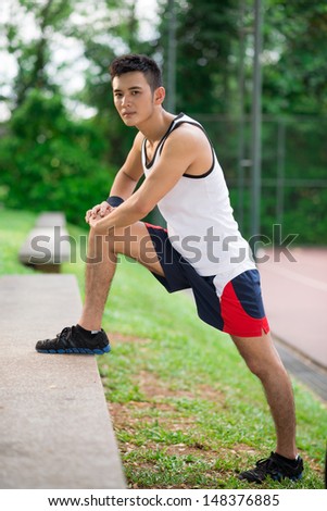 Vertical portrait of a sportsman doing warm-up exercises in the park