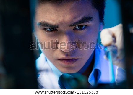 Close-up of a young electronic engineer busy with repairing on the foreground