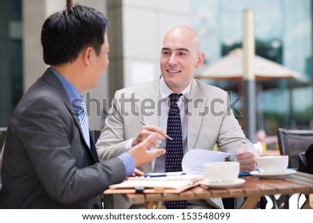 Business co-workers dealing together at a cafe on the foreground