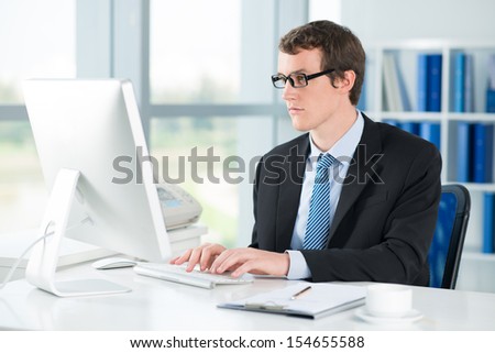 Image of a young businessman typing on computer at the office
