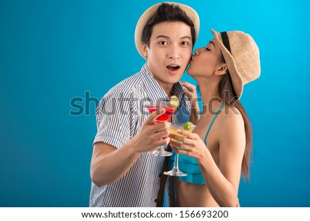 Copy-space image of a couple in-love where the girlfriend's kissing his boyfriends while heÃ?Â¢?? surprising isolated on blue