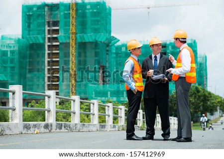 Copy-spaced image of modern engineers discussing something outside
