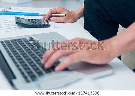 Cropped image of a financial consultant counting something using a calculator and a laptop on the foreground