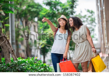 Copy-spaced image of young shopaholics pointing at the mall standing outside