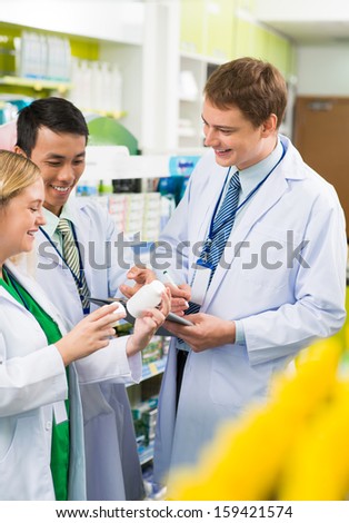 Vertical image of young pharmacists working in the chemists together on the foreground