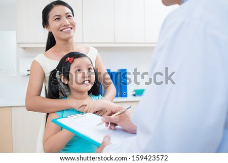 Image of a happy daughter with her mom listening to the doctor\'s opinion on the foreground