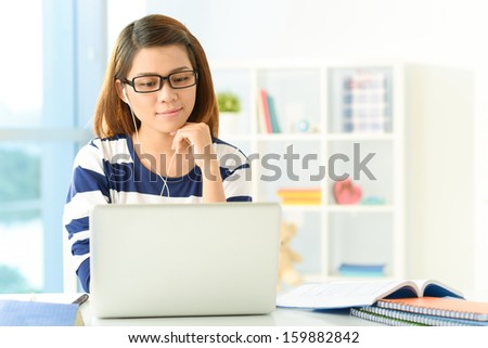Copy-spaced image of a student girl studying something using computer at home