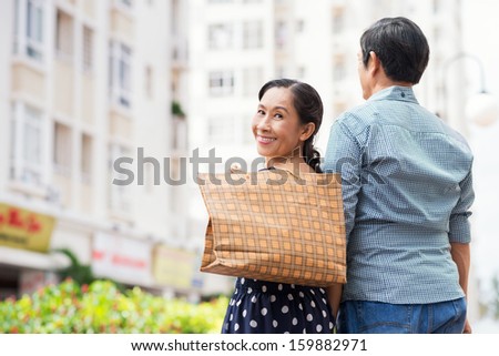Copy-spaced portrait of a happy senior woman after shopping with her husband smiling and looking at camera on the foreground