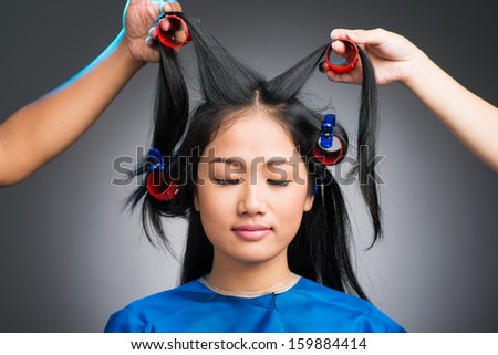 Isolated image of a young woman having her hair curled by special equipment