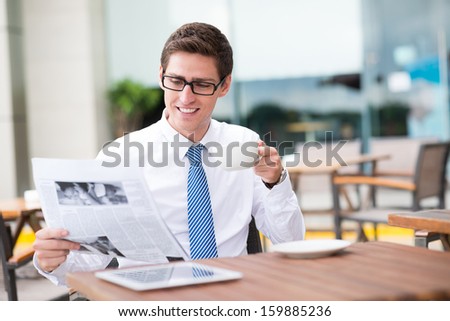 Copy-spaced image of a young businessman drinking tea while reading the newspaper on the foreground