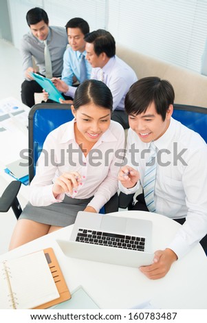 Vertical image of business co-workers networking while using computer on the foreground