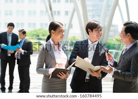 Copy-spaced image of a young business team discussing something outside on the foreground