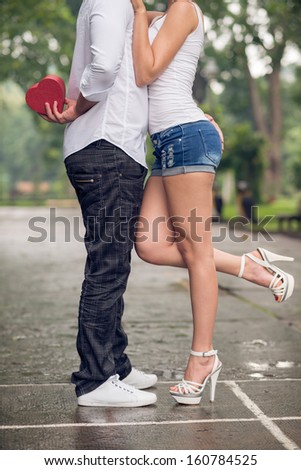 Cropped image of a young couple in-love where a boyfriend holding a giftbox for his girlfriend outside