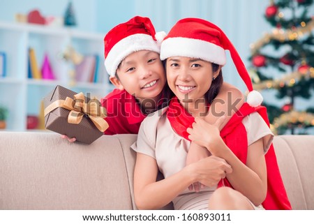 Portrait of happy little boy and his mother looking at camera on Christmas evening